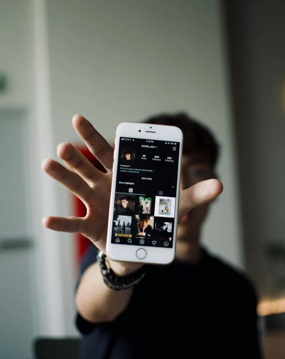 Person holding up a phone showing a social media profile