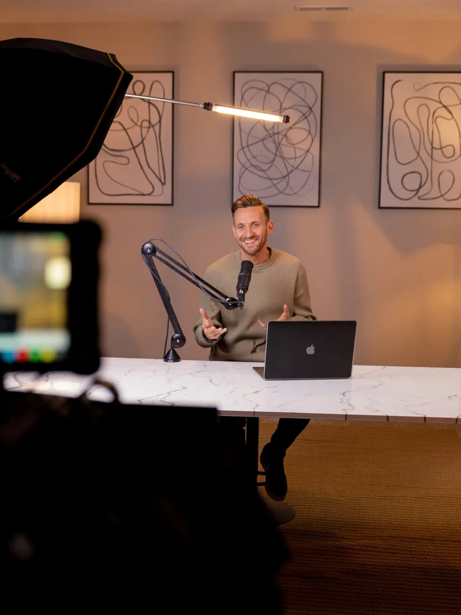 Creator filming a podcast with a microphone and laptop
